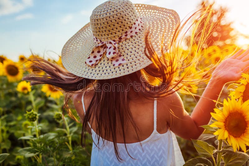 Mujer joven que camina en campo floreciente del girasol, saltando y divirtiéndose Vacaciones de verano fotos de archivo libres de regalías Mujer joven que camina en campo floreciente del girasol, saltando y divirtiéndose Vacaciones de verano fotos de archivo libres de regalías
