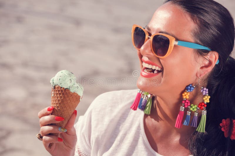 Mujer joven que come el helado en la calle imagen de archivo libre de regalías Mujer joven que come el helado en la calle imagen de archivo libre de regalías