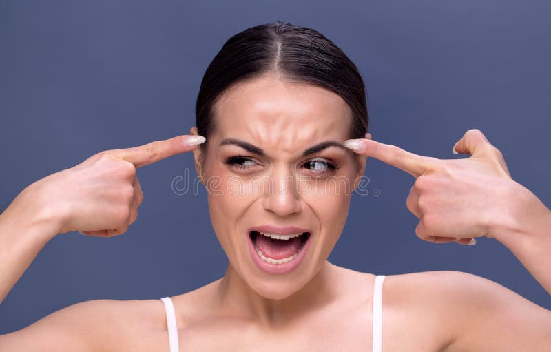 Mujer joven que comprueba arrugas en su frente fotografía de archivo Mujer joven que comprueba arrugas en su frente fotografía de archivo