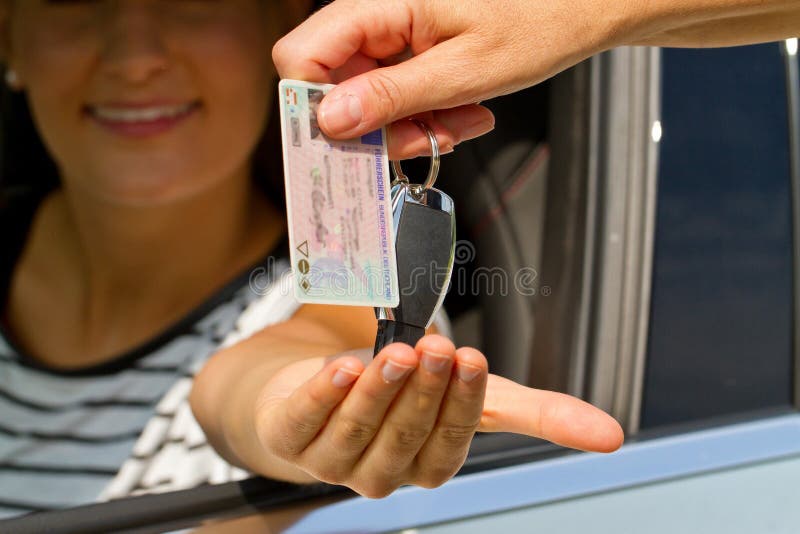 Mujer joven que consigue su llave del carné de conducir y del coche fotos de archivo Mujer joven que consigue su llave del carné de conducir y del coche fotos de archivo