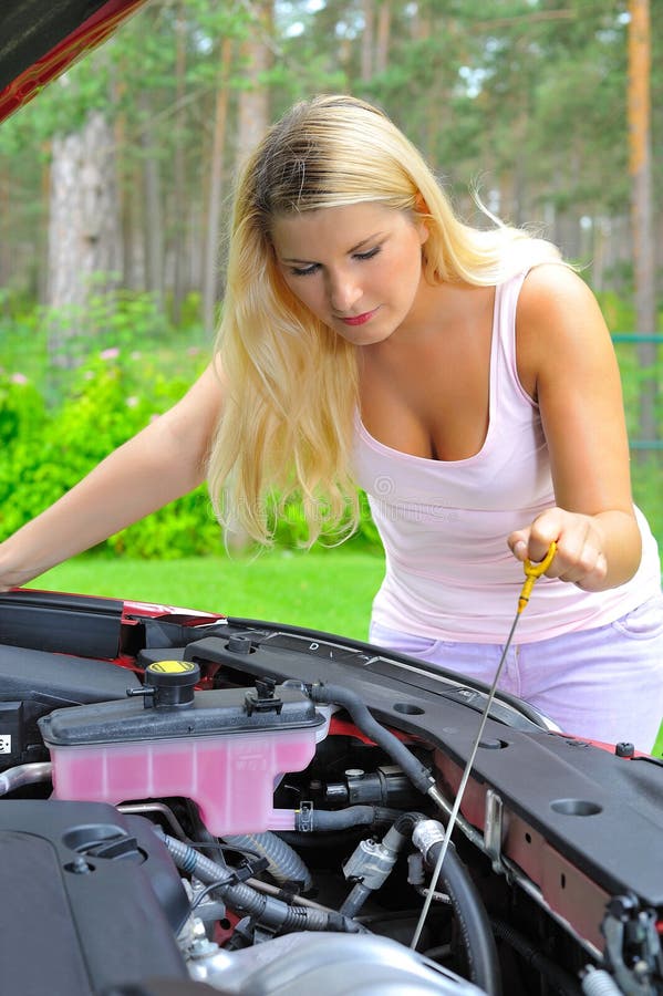 Young woman checking oil level in the car outdoors. Young woman checking oil level in the car outdoors