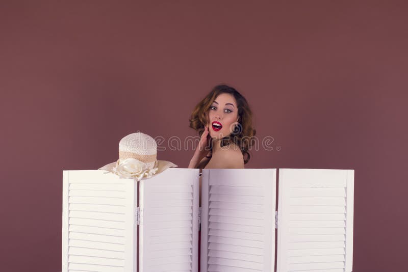 Mujer joven que desnuda detrás de una pantalla fotografía de archivo Mujer joven que desnuda detrás de una pantalla fotografía de archivo