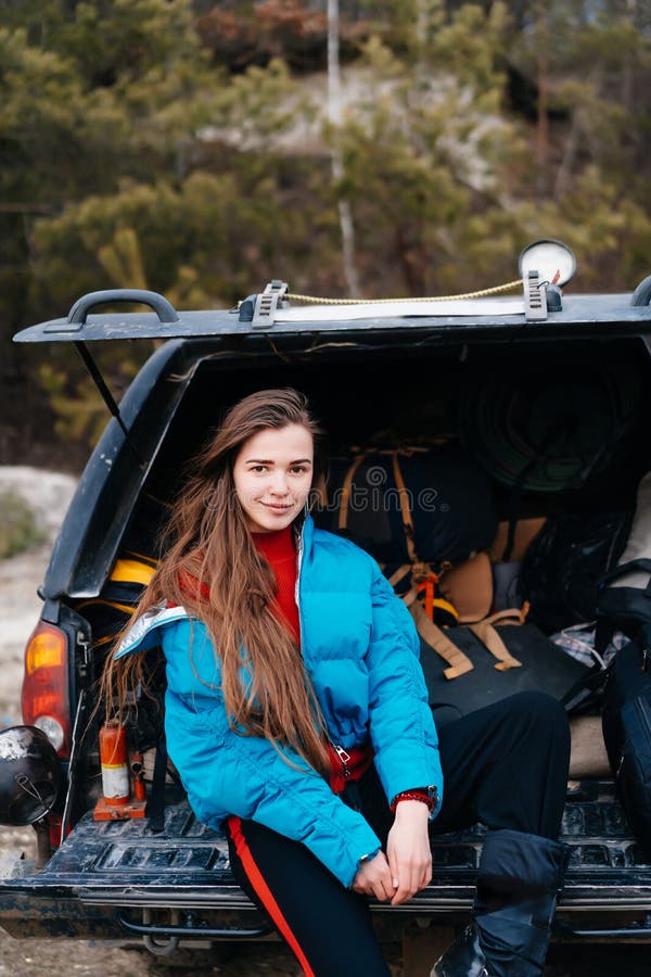 Mujer joven que disfruta de la naturaleza mientras que se sienta en el tronco de coche fotos de archivo libres de regalías Mujer joven que disfruta de la naturaleza mientras que se sienta en el tronco de coche fotos de archivo libres de regalías