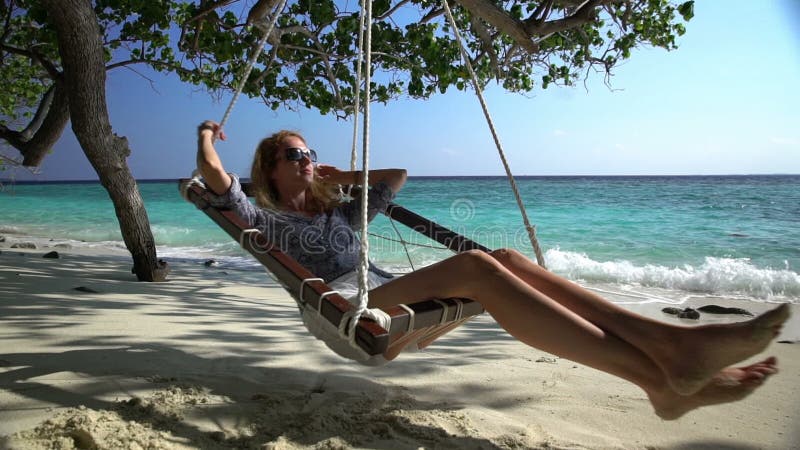 Mujer joven que disfruta de un resto en una hamaca en la playa tropical