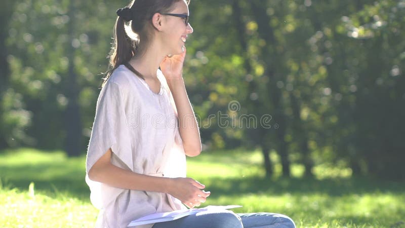 Mujer joven que escucha la música y que usa smartphone en el parque