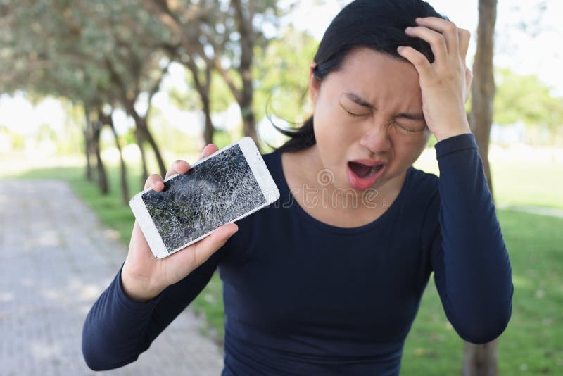 Mujer joven que grita en rabia con un smartphone quebrado fotos de archivo libres de regalías