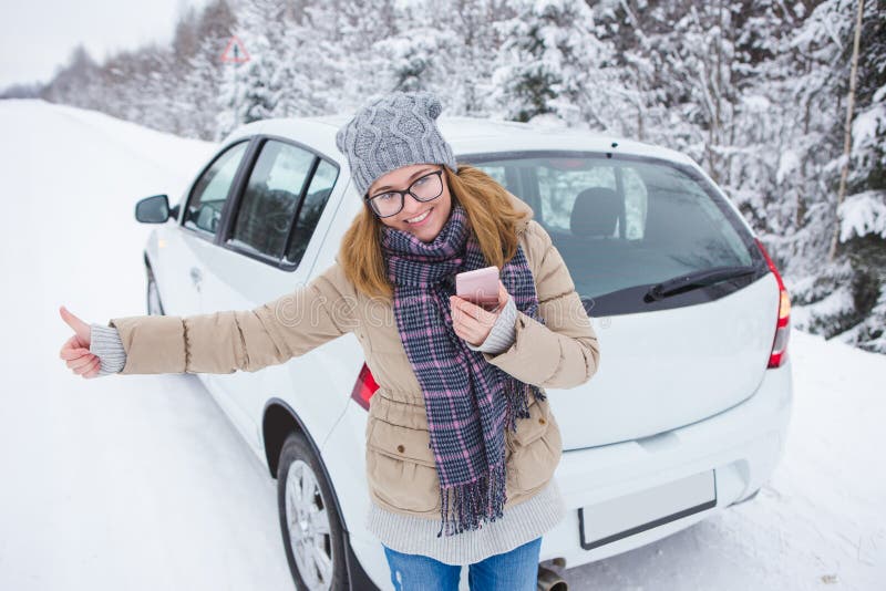 Mujer joven que hace autostop en el camino nevado del invierno fotos de archivo Mujer joven que hace autostop en el camino nevado del invierno fotos de archivo