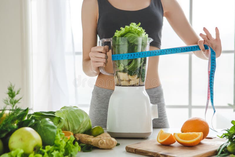 Mujer joven que hace el smoothie del detox en casa fotos de archivo libres de regalías Mujer joven que hace el smoothie del detox en casa fotos de archivo libres de regalías