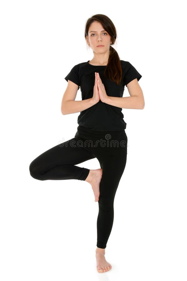 Mujer joven que hace la actitud Vrksasana del árbol del asana de la yoga