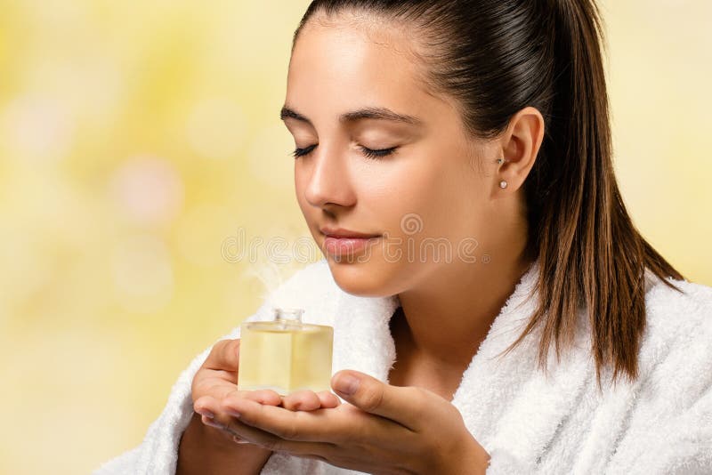 Mujer joven que huele fragancia del aceite esencial