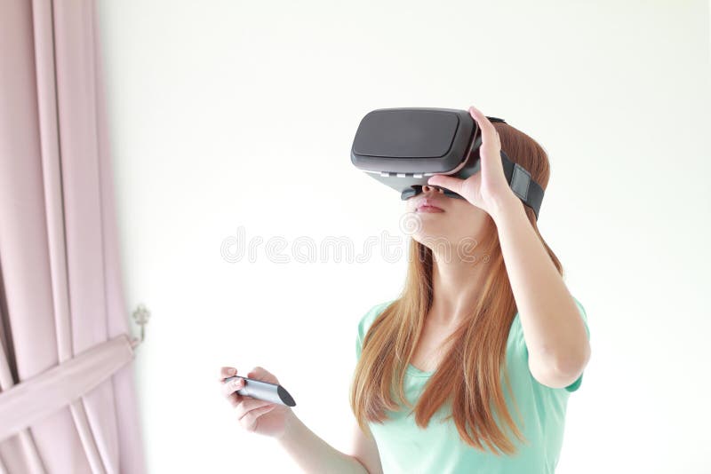 Mujer joven que lleva los vidrios de la realidad virtual en casa fotografía de archivo libre de regalías Mujer joven que lleva los vidrios de la realidad virtual en casa fotografía de archivo libre de regalías