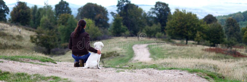 Mujer joven que mira en horizonte con el perrito imagen de archivo Mujer joven que mira en horizonte con el perrito imagen de archivo