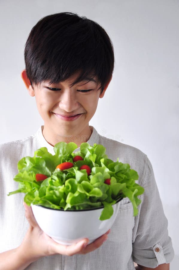 Mujer joven que mira su cuenco de ensalada imagen de archivo libre de regalías Mujer joven que mira su cuenco de ensalada imagen de archivo libre de regalías