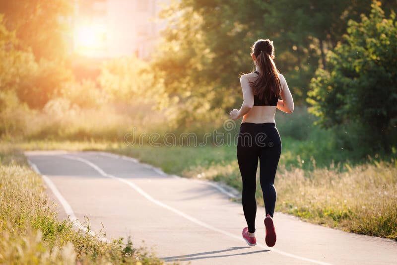 Mujer joven que se ejecuta en parque imagen de archivo Mujer joven que se ejecuta en parque imagen de archivo