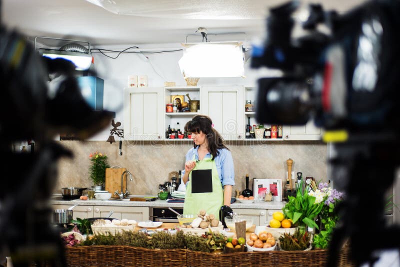 Young brunette woman preparing for a cooking show, surrounded by video cameras. Young brunette woman preparing for a cooking show, surrounded by video cameras