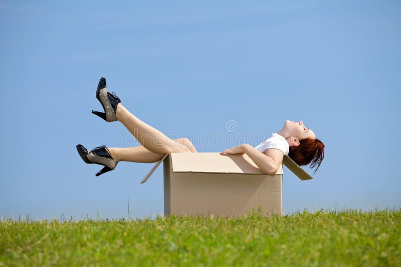 Mujer joven que se sienta en caja de cartón en el parque imagen de archivo libre de regalías Mujer joven que se sienta en caja de cartón en el parque imagen de archivo libre de regalías