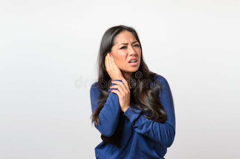 Mujer joven que se sostiene el oído doloroso imagen de archivo libre de regalías Mujer joven que se sostiene el oído doloroso imagen de archivo libre de regalías