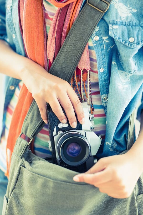 Mujer joven que toma la cámara de su bolso fotografía de archivo Mujer joven que toma la cámara de su bolso fotografía de archivo