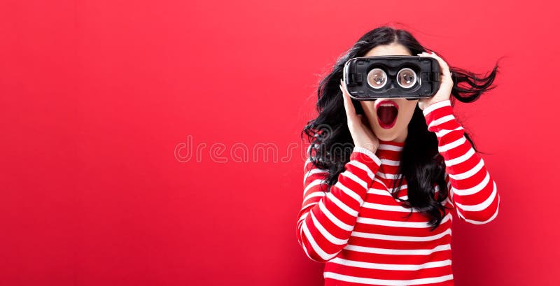 Mujer joven que usa las auriculares de la realidad virtual