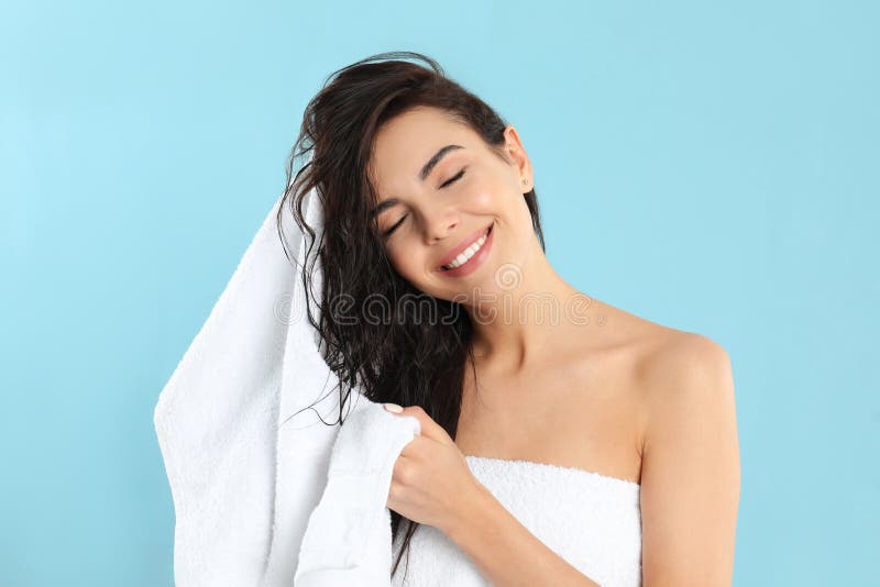 Mujer joven secando el pelo con toalla de fondo azul