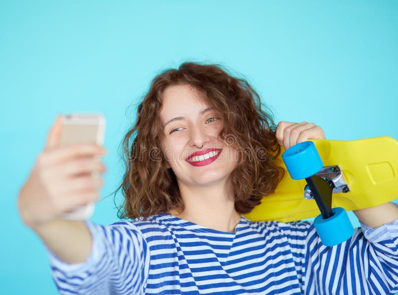 Mujer joven sonriente hermosa con el monopatín amarillo brillante fotografía de archivo libre de regalías Mujer joven sonriente hermosa con el monopatín amarillo brillante fotografía de archivo libre de regalías