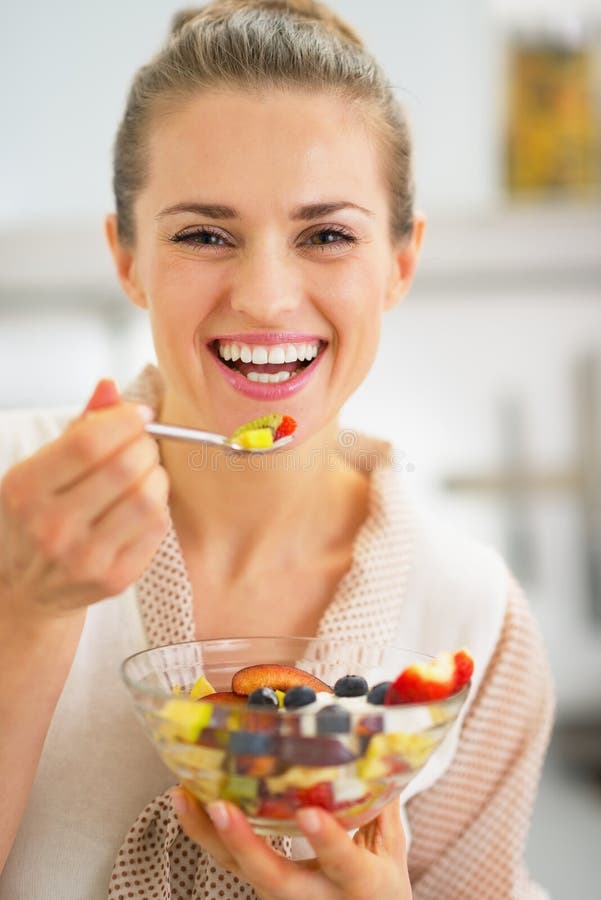 Mujer joven sonriente que come la ensalada de fruta fresca imágenes de archivo libres de regalías Mujer joven sonriente que come la ensalada de fruta fresca imágenes de archivo libres de regalías