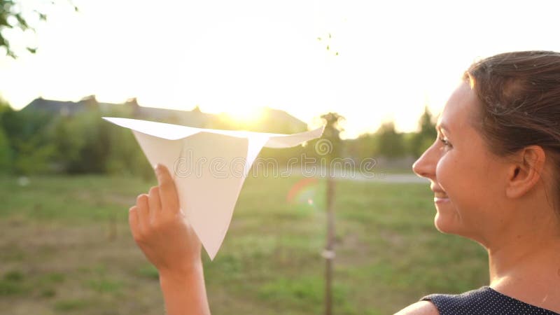 Mujer lanza avión de papel en el fondo del atardecer Soñando con viajar o con la profesión de una azafata almacen de video