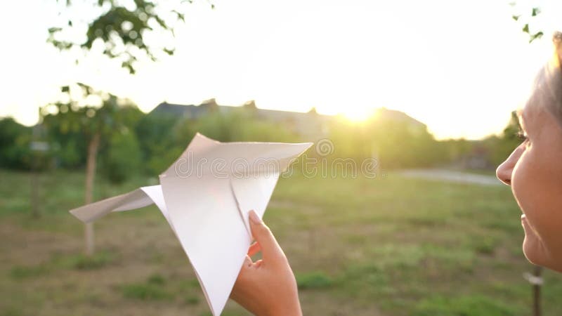 Mujer lanza avión de papel en el fondo del atardecer Soñando con viajar o con la profesión de una azafata Lento almacen de metraje de vídeo