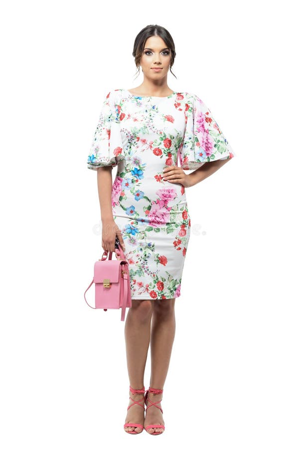 Mujer latina magnífica en vestido de flores con el peinado del bollo que sostiene el bolso fotografía de archivo libre de regalías Mujer latina magnífica en vestido de flores con el peinado del bollo que sostiene el bolso fotografía de archivo libre de regalías