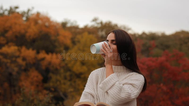 Mujer leyendo libro sentado en el bosque de otoño