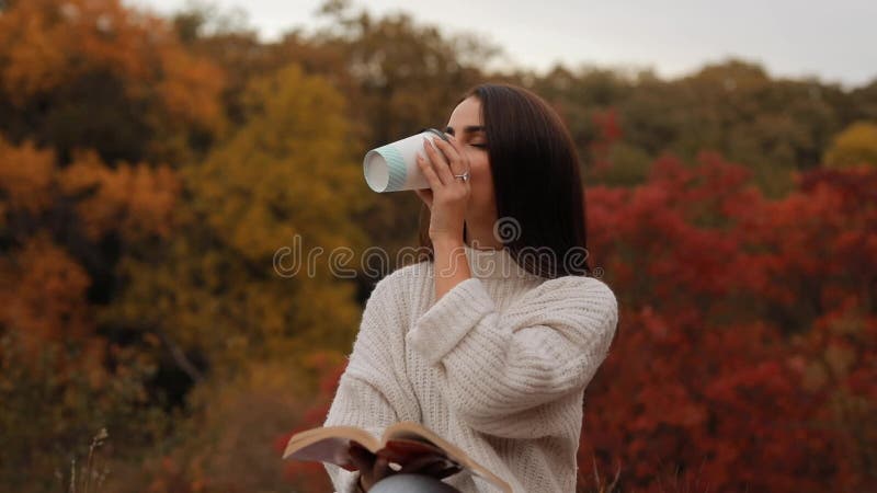 Mujer leyendo libro sentado en el bosque de otoÃ±o Mujer leyendo libro sentado en un suelo en la naturaleza tomando tÃ©, colorido