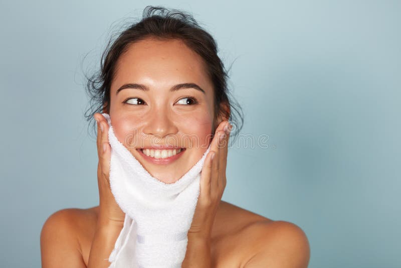 Mujer limpiando la piel facial con toalla después del retrato de la cara de lavado