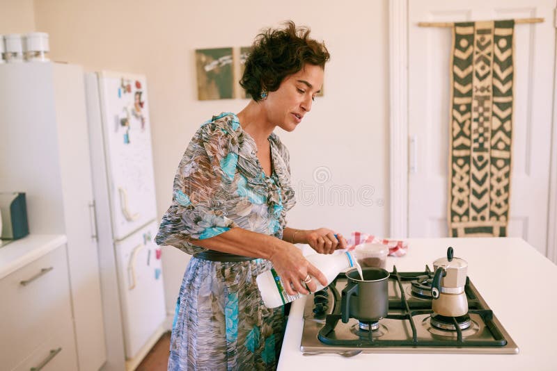 Mujer madura ocupada haciendo su taza de la mañana del café en casa imagenes de archivo Mujer madura ocupada haciendo su taza de la mañana del café en casa imagenes de archivo