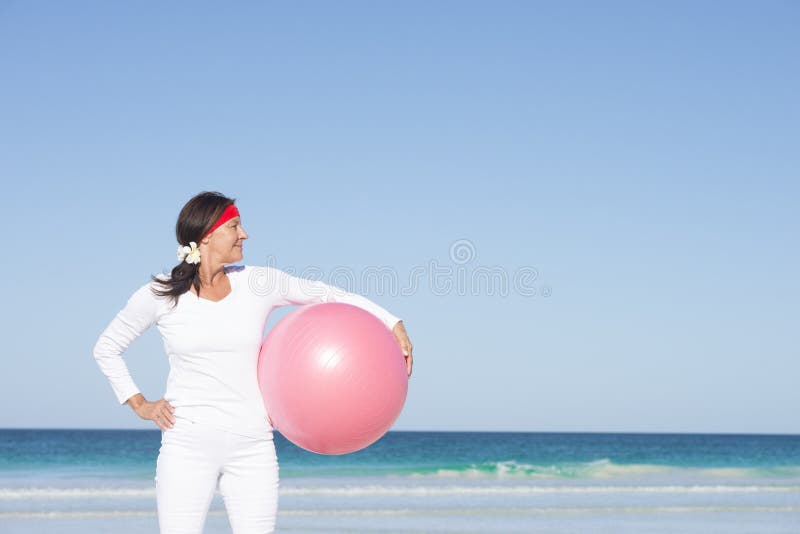 Mujer madura sana apta que ejercita en la playa imagenes de archivo Mujer madura sana apta que ejercita en la playa imagenes de archivo