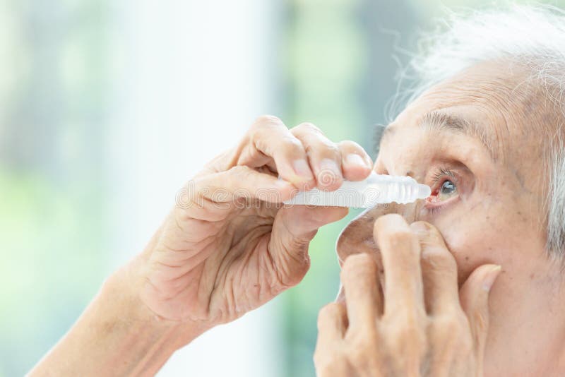 Mujer mayor asiática que pone el descenso de ojo, opinión del primer la persona mayor que usa la botella de eyedrops en sus ojo foto de archivo Mujer mayor asiática que pone el descenso de ojo, opinión del primer la persona mayor que usa la botella de eyedrops en sus ojo foto de archivo