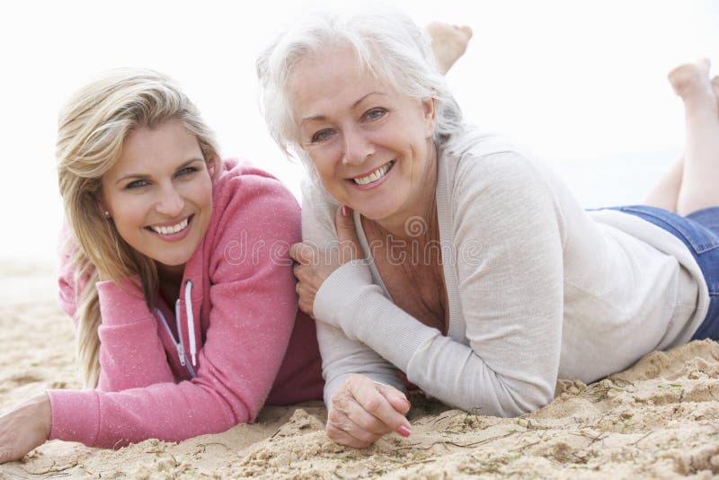 Mujer mayor con la hija adulta que se relaja en la playa foto de archivo Mujer mayor con la hija adulta que se relaja en la playa foto de archivo