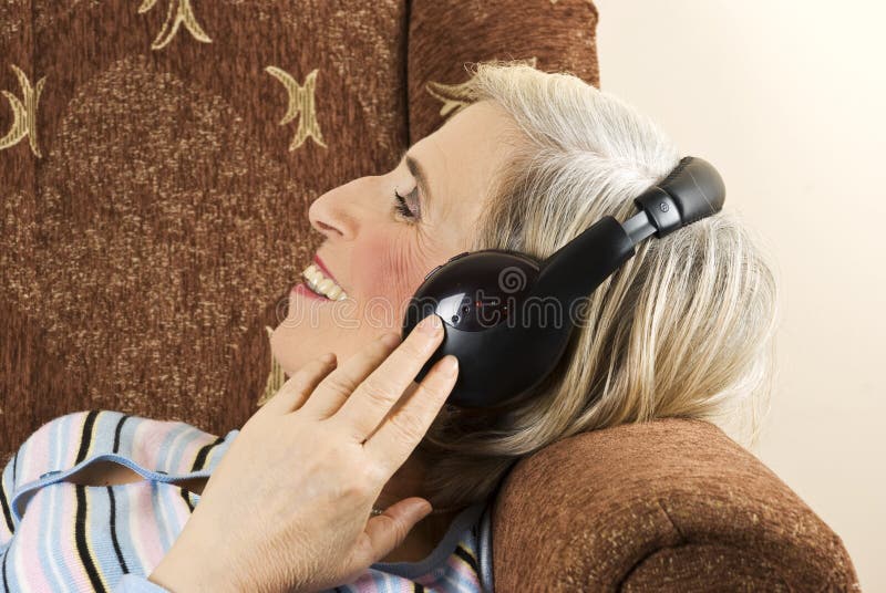 Mujer mayor con los auriculares en sofá