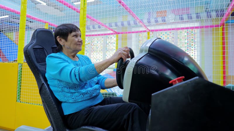 Mujer mayor divirtiéndose mientras conduce un simulador de coche