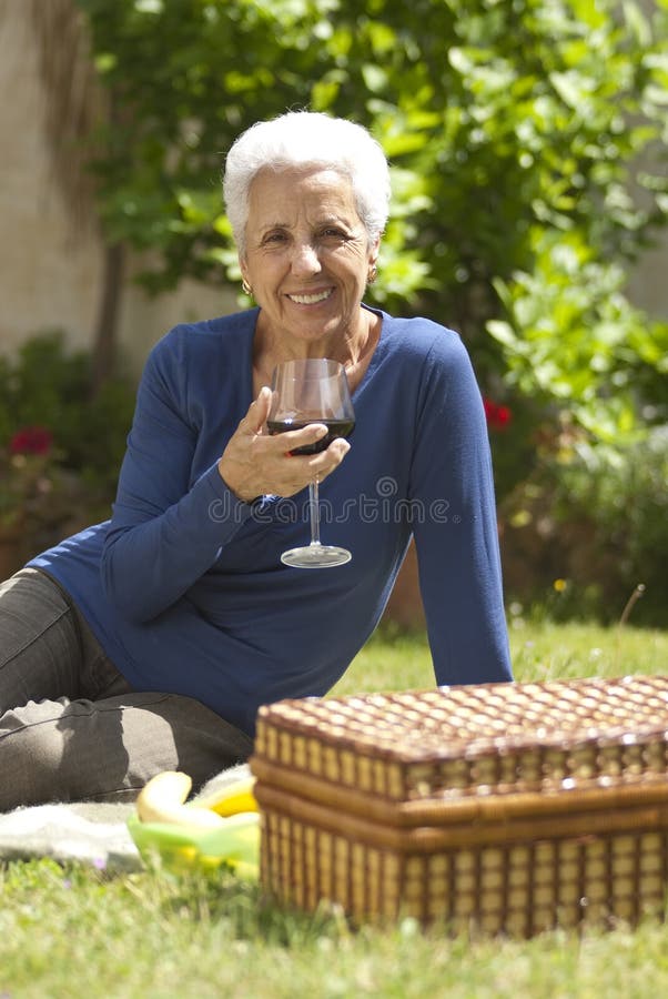 Mujer mayor encantadora que goza de un vidrio de vino rojo fotografía de archivo libre de regalías Mujer mayor encantadora que goza de un vidrio de vino rojo fotografía de archivo libre de regalías