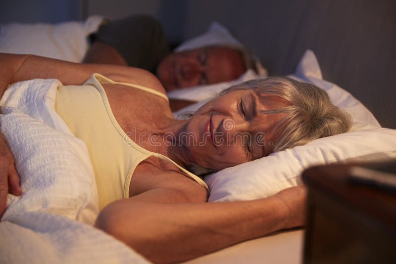 Mujer mayor pacífica dormida en cama en la noche fotografía de archivo libre de regalías Mujer mayor pacífica dormida en cama en la noche fotografía de archivo libre de regalías