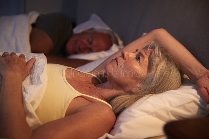 Mujer mayor preocupante en cama en la noche que sufre con insomnio