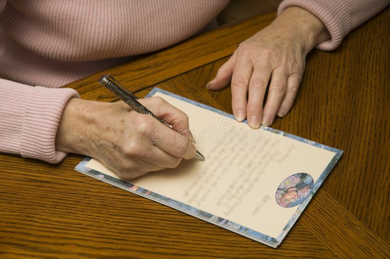 Mujer mayor que escribe una letra con la pluma y el papel