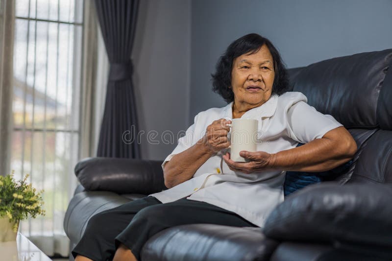 Mujer mayor que habla y que bebe una taza de agua foto de archivo libre de regalías Mujer mayor que habla y que bebe una taza de agua foto de archivo libre de regalías