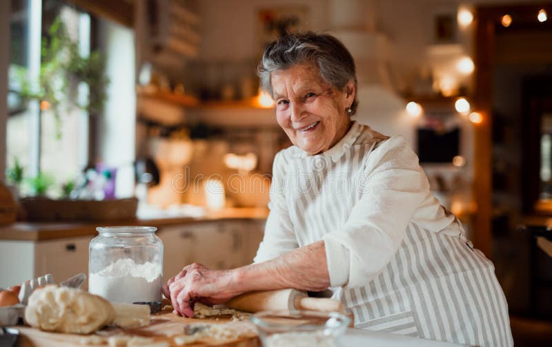 An elderly woman making cakes in a kitchen at home. Copy space. An elderly woman making cakes in a kitchen at home. Copy space.