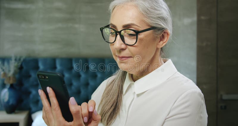 Mujer mayor que manda un SMS en smartphone