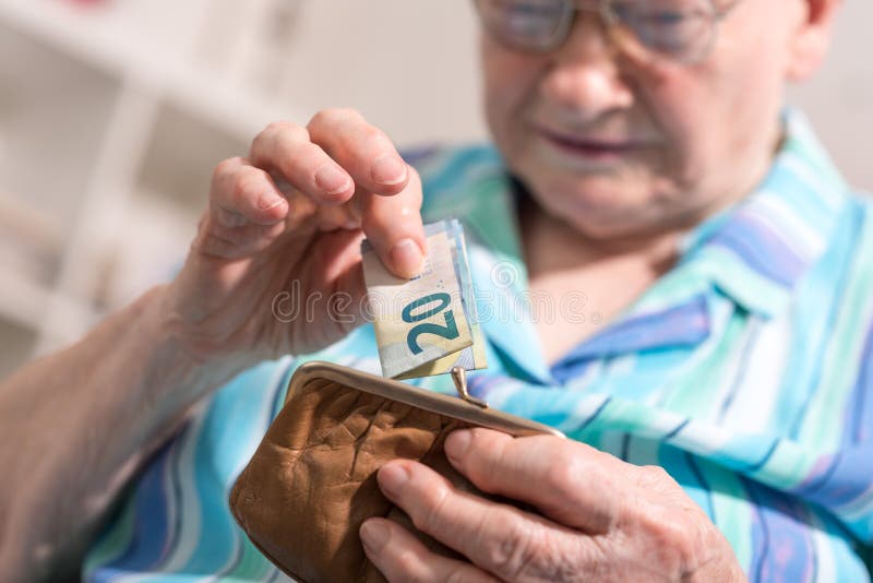 Mujer mayor que saca un billete de banco de su cartera fotos de archivo Mujer mayor que saca un billete de banco de su cartera fotos de archivo