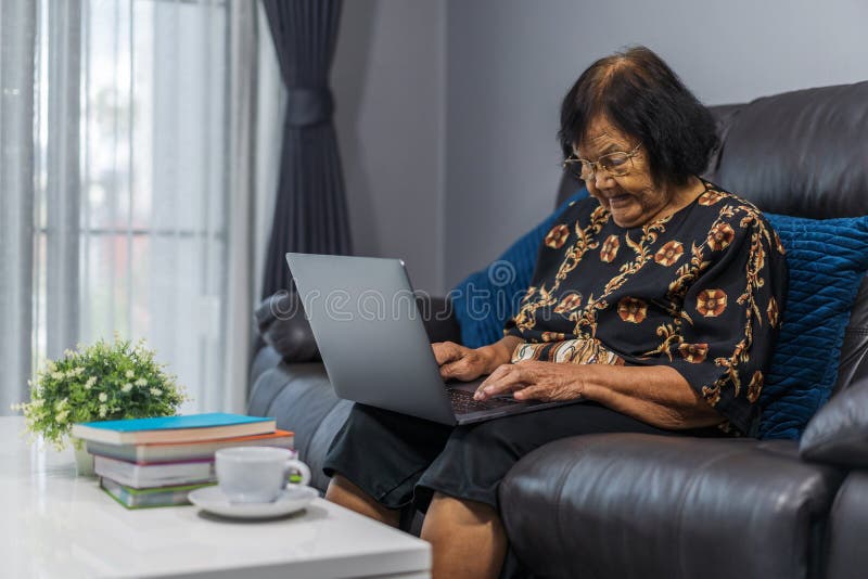 Mujer mayor que trabaja en el ordenador portátil en sala de estar imágenes de archivo libres de regalías Mujer mayor que trabaja en el ordenador portátil en sala de estar imágenes de archivo libres de regalías