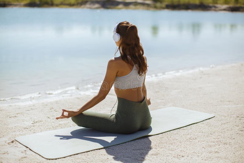 Mujer meditando en yoga posando en la playa fotografía de archivo Mujer meditando en yoga posando en la playa fotografía de archivo
