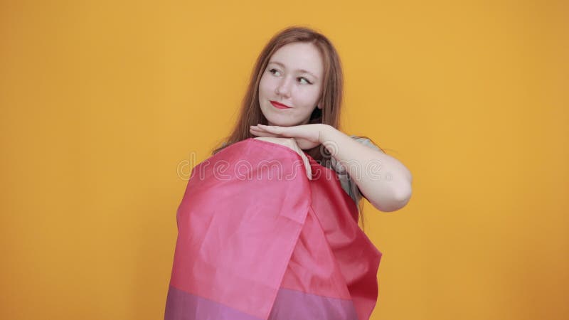 Mujer mirando a un lado, con las manos bajo el mentón, cubierta bandera bisexual