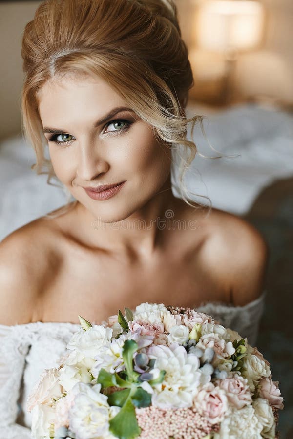 Mujer modelo rubia hermosa y feliz con los ojos verdes en un vestido del cordón que se casa con un ramo de flores en su mano imagen de archivo libre de regalías Mujer modelo rubia hermosa y feliz con los ojos verdes en un vestido del cordón que se casa con un ramo de flores en su mano imagen de archivo libre de regalías